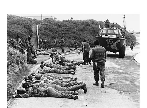 En Ross Road, Puerto Argentino, los marines deponen sus armas frente a los comandos anfibios de la Armada Argentina. E